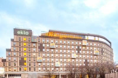 Façade d'un bâtiment moderne avec de grandes fenêtres, des arbres devant et une entrée vitrée portant le nom ’Eklo’.
