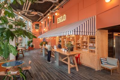 Façade d'un bâtiment moderne avec de grandes fenêtres, des arbres devant et une entrée vitrée portant le nom ’Eklo’.