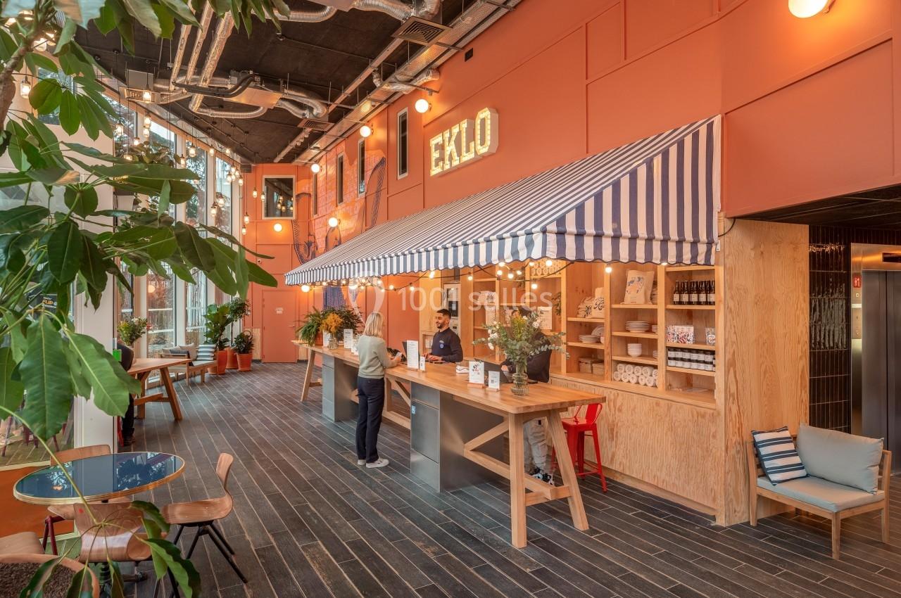 Espace d'accueil lumineux avec un comptoir en bois, une enseigne ’Eklo’, des plantes et une décoration chaleureuse.