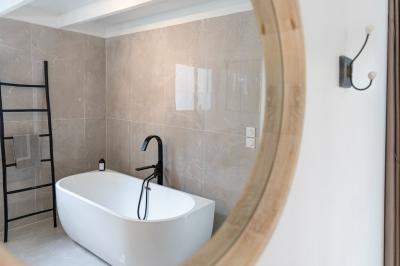 Chambre lumineuse avec lit double, étagère, fenêtre donnant sur l'extérieur et salle de bain attenante avec lavabo moderne.