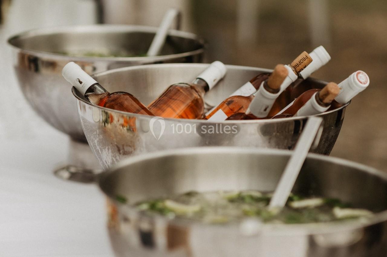Bouteilles de vin rosé et glaçons dans des seaux en métal sur une table lors d'un événement en extérieur.