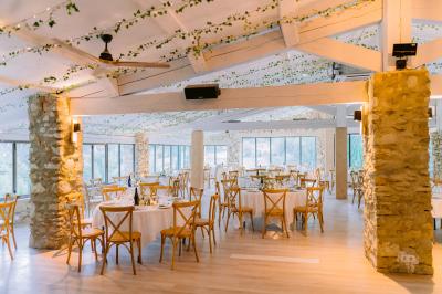 Miniature Location salle Valouse (Drôme) - Hameau de Valouse #24 Salle lumineuse avec tables et chaises en bois, grandes baies vitrées et plafond décoré de motifs végétaux.