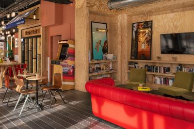 Façade d'un bâtiment moderne avec une enseigne lumineuse ’eklo’, des baies vitrées et des tables en terrasse.