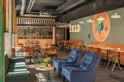 Façade d'un bâtiment moderne avec une enseigne lumineuse ’eklo’, des baies vitrées et des tables en terrasse.