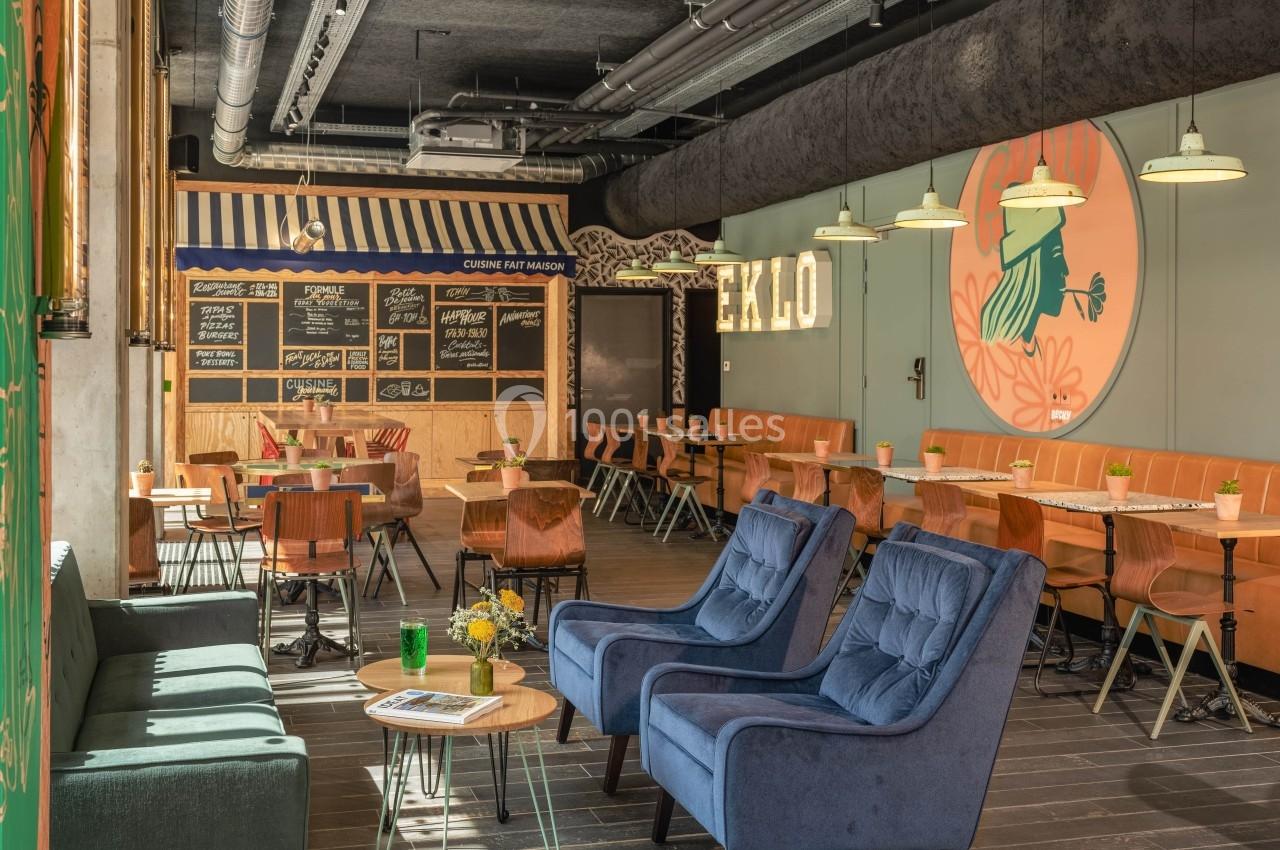 Salle de restaurant moderne avec mobilier coloré, tableaux de menus au mur et décoration lumineuse.