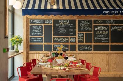 Façade d'un bâtiment moderne avec une enseigne lumineuse ’eklo’, des baies vitrées et des tables en terrasse.