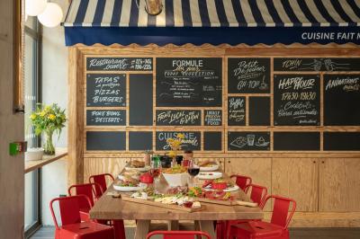 Façade d'un bâtiment moderne avec enseigne lumineuse ’eklo’, terrasse aménagée et intérieur éclairé visible.