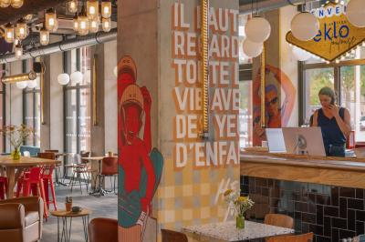 Façade d'un bâtiment moderne avec enseigne lumineuse ’eklo’, terrasse aménagée et intérieur éclairé visible.