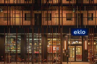 Façade d'un bâtiment moderne avec enseigne lumineuse ’eklo’, terrasse aménagée et intérieur éclairé visible.