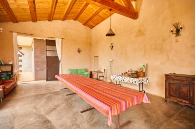 Petite pièce avec plafond en bois, coin cuisine équipé, table en bois et buffet rustique, vue sur une porte ouverte.