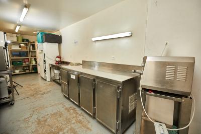 Petite pièce avec plafond en bois, coin cuisine équipé, table en bois et buffet rustique, vue sur une porte ouverte.