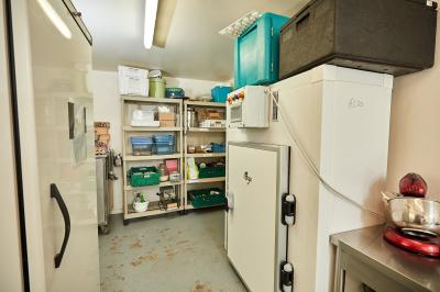 Petite pièce avec plafond en bois, coin cuisine équipé, table en bois et buffet rustique, vue sur une porte ouverte.