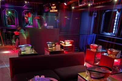 Banquettes violettes entourant des tables basses avec des seaux à champagne dans un intérieur sombre et éclairage tamisé.