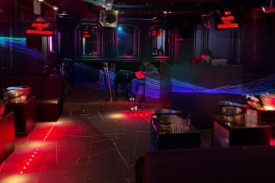 Banquettes violettes entourant des tables basses avec des seaux à champagne dans un intérieur sombre et éclairage tamisé.