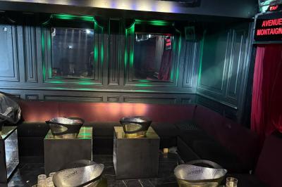 Banquettes violettes entourant des tables basses avec des seaux à champagne dans un intérieur sombre et éclairage tamisé.