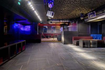 Banquettes violettes entourant des tables basses avec des seaux à champagne dans un intérieur sombre et éclairage tamisé.