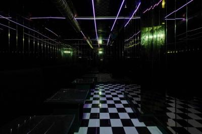 Banquettes violettes entourant des tables basses avec des seaux à champagne dans un intérieur sombre et éclairage tamisé.