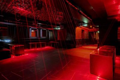 Banquettes violettes entourant des tables basses avec des seaux à champagne dans un intérieur sombre et éclairage tamisé.