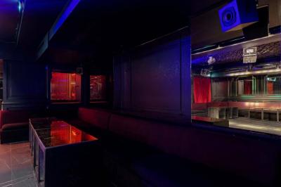 Banquettes violettes entourant des tables basses avec des seaux à champagne dans un intérieur sombre et éclairage tamisé.