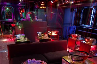 Banquettes noires et violettes entourant des tables basses avec des seaux à champagne dans un espace sombre et éclairé.