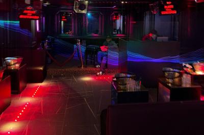 Banquettes noires et violettes entourant des tables basses avec des seaux à champagne dans un espace sombre et éclairé.