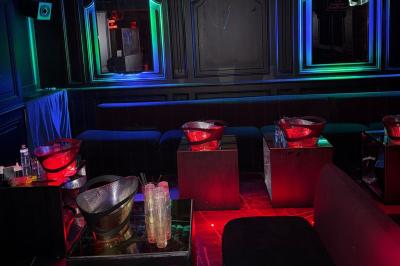 Banquettes noires et violettes entourant des tables basses avec des seaux à champagne dans un espace sombre et éclairé.