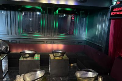 Banquettes noires et violettes entourant des tables basses avec des seaux à champagne dans un espace sombre et éclairé.