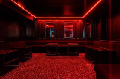 Banquettes noires et violettes entourant des tables basses avec des seaux à champagne dans un espace sombre et éclairé.