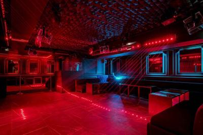 Banquettes noires et violettes entourant des tables basses avec des seaux à champagne dans un espace sombre et éclairé.