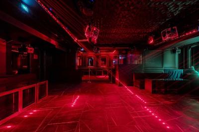 Banquettes noires et violettes entourant des tables basses avec des seaux à champagne dans un espace sombre et éclairé.