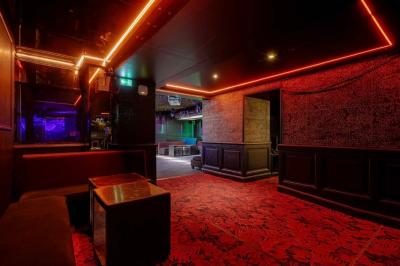 Banquettes noires et violettes entourant des tables basses avec des seaux à champagne dans un espace sombre et éclairé.