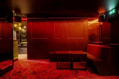 Banquettes noires et violettes entourant des tables basses avec des seaux à champagne dans un espace sombre et éclairé.