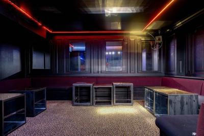 Banquettes noires et violettes entourant des tables basses avec des seaux à champagne dans un espace sombre et éclairé.