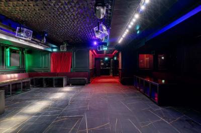 Banquettes noires et violettes entourant des tables basses avec des seaux à champagne dans un espace sombre et éclairé.