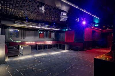 Banquettes noires et violettes entourant des tables basses avec des seaux à champagne dans un espace sombre et éclairé.