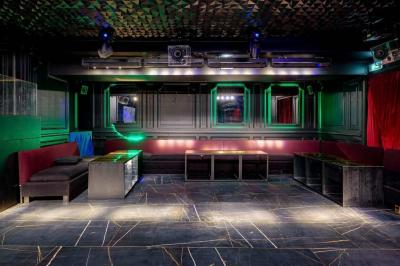 Banquettes noires et violettes entourant des tables basses avec des seaux à champagne dans un espace sombre et éclairé.