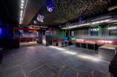 Banquettes noires et violettes entourant des tables basses avec des seaux à champagne dans un espace sombre et éclairé.