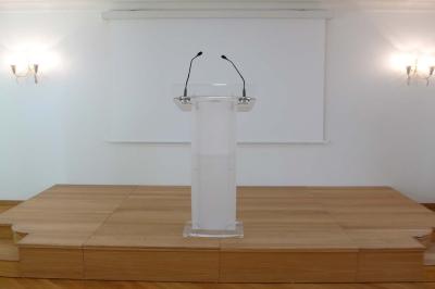Vue d'un jardin arboré avec des tables et chaises, jouxtant un parking contenant plusieurs voitures.