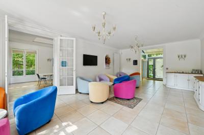 Vue d'un jardin arboré avec des tables et chaises, jouxtant un parking contenant plusieurs voitures.