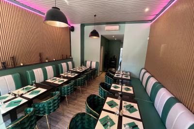 Banquettes rouges et tables noires dans un café à la décoration rétro avec guitares accrochées aux murs.