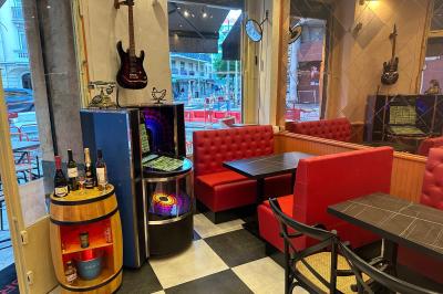 Banquettes rouges et tables noires dans un café à la décoration rétro avec guitares accrochées aux murs.