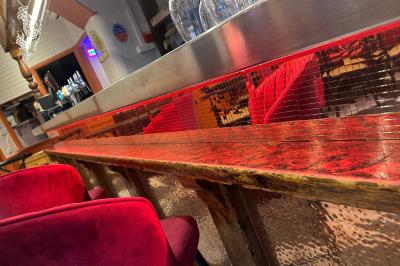 Banquettes rouges et tables noires dans un café à la décoration rétro avec guitares accrochées aux murs.