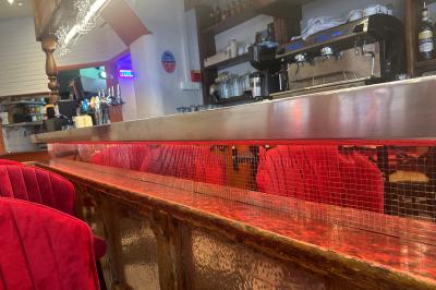 Banquettes rouges et tables noires dans un café à la décoration rétro avec guitares accrochées aux murs.