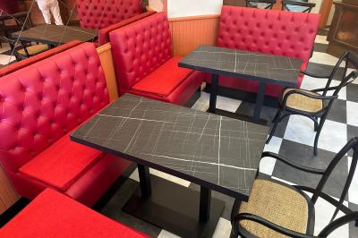 Banquettes rouges et tables noires dans un café à la décoration rétro avec guitares accrochées aux murs.
