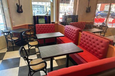 Banquettes rouges et tables noires dans un café à la décoration rétro avec guitares accrochées aux murs.
