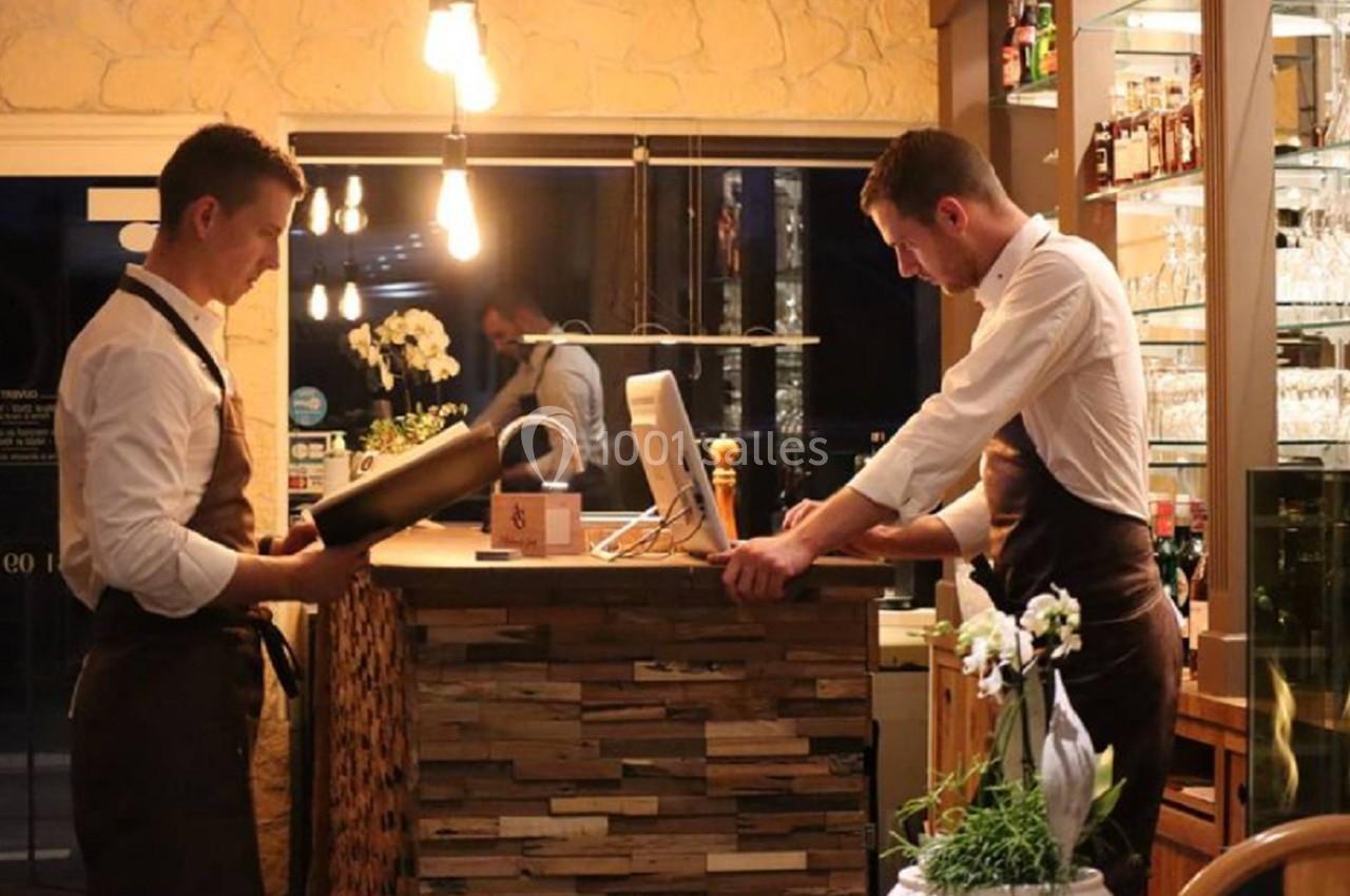 Deux serveurs en tablier travaillent au comptoir d'un restaurant éclairé par une lumière chaleureuse.