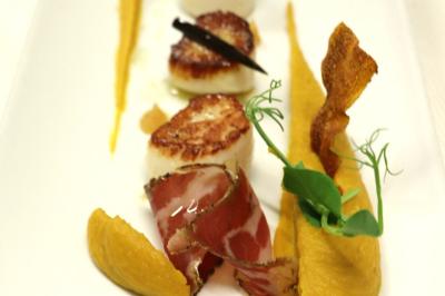 Noix de Saint-Jacques poêlées avec purée de légumes, chips croustillante et garniture de jambon et herbes fraîches.