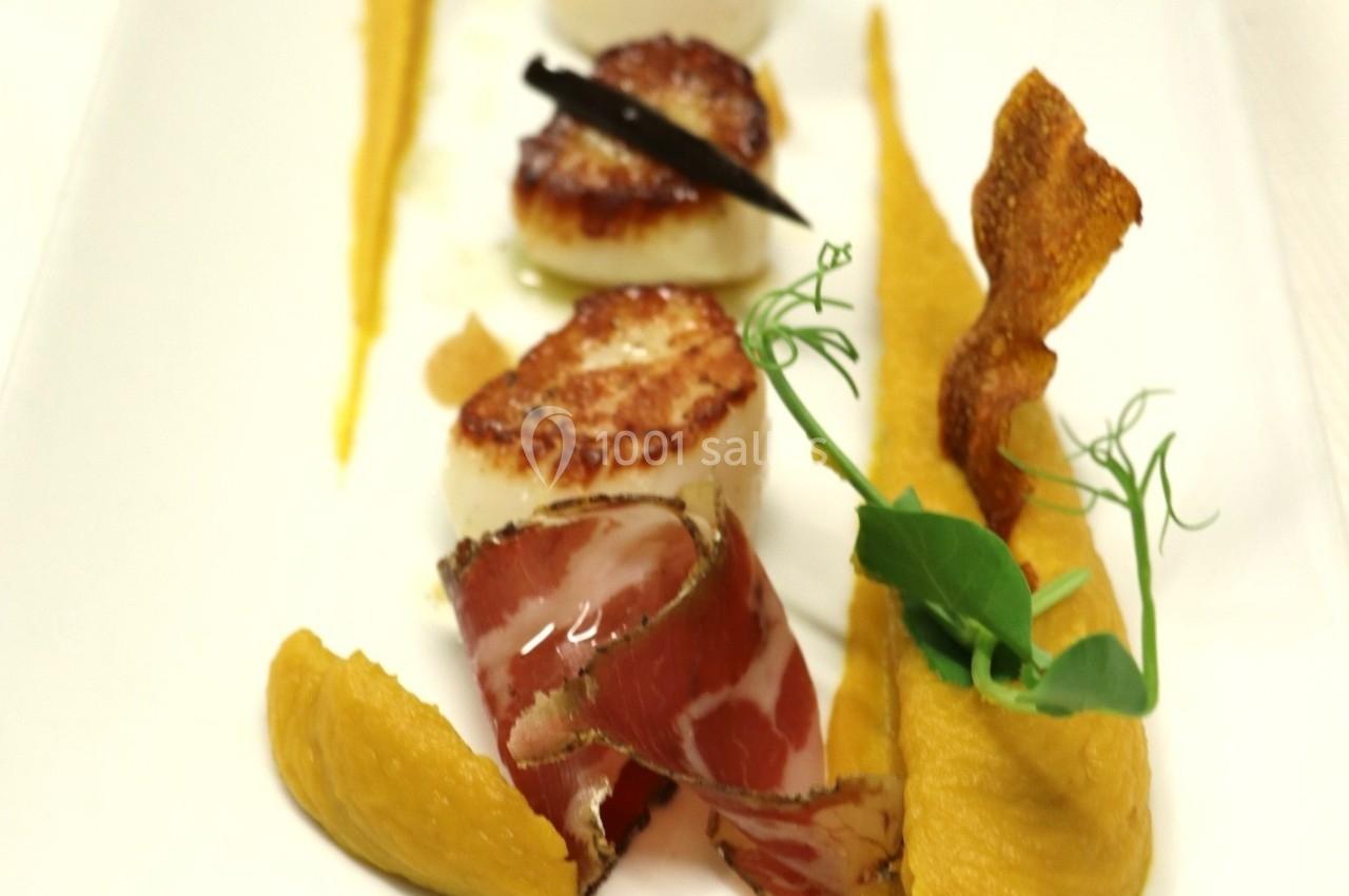 Noix de Saint-Jacques poêlées avec purée de légumes, chips croustillante et garniture de jambon et herbes fraîches.