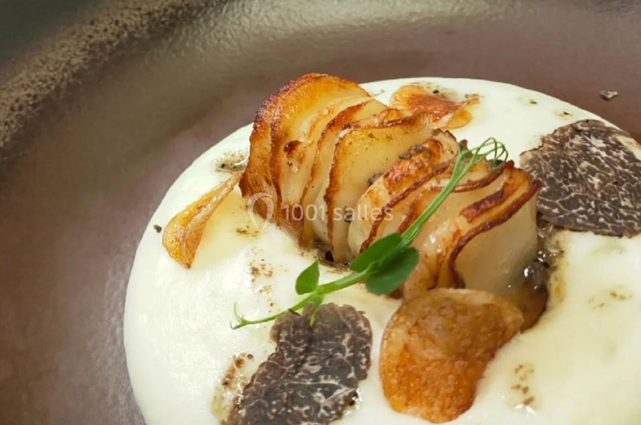 Purée onctueuse garnie de tranches de pommes de terre dorées, truffes noires et herbes fraîches.