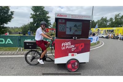 Deux personnes discutent gestuellement lors d'une soirée avec une DJ en arrière-plan et des lumières colorées.